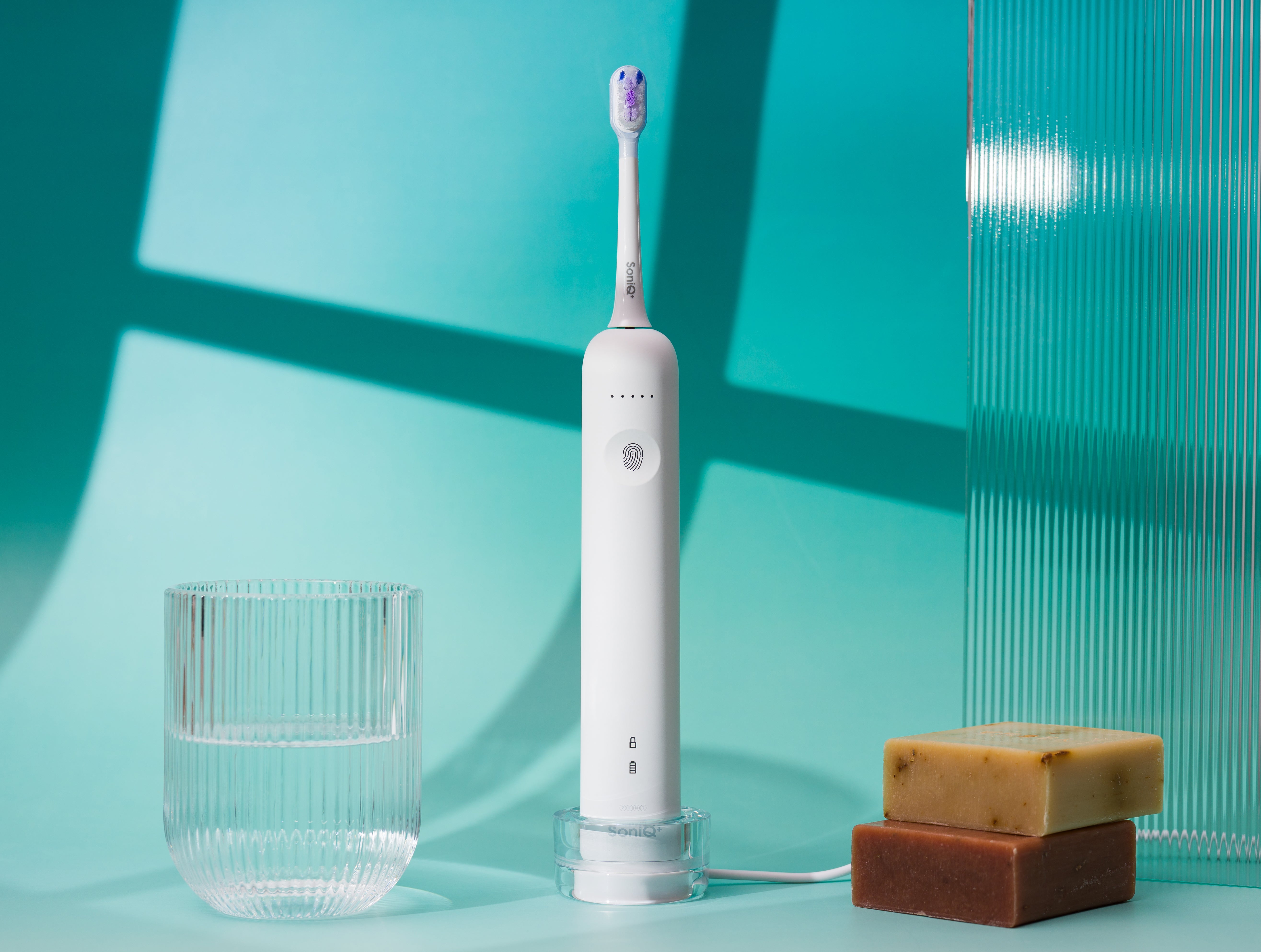 ZENT® SoniQ™ – Aktywna szczoteczka soniczna z ruchem oscylacyjnym 40°, obok leży szklanka wody, a po drugiej stronie dwie kostki mydła