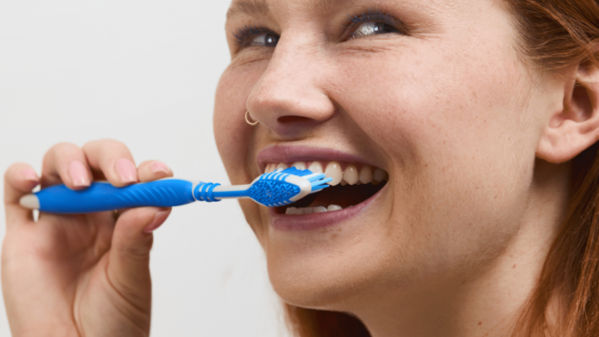 Kobieta na zdjęciu myje zęby szczoteczką do zębów. 10 najczęstszych błędów w pielęgnacji zębów