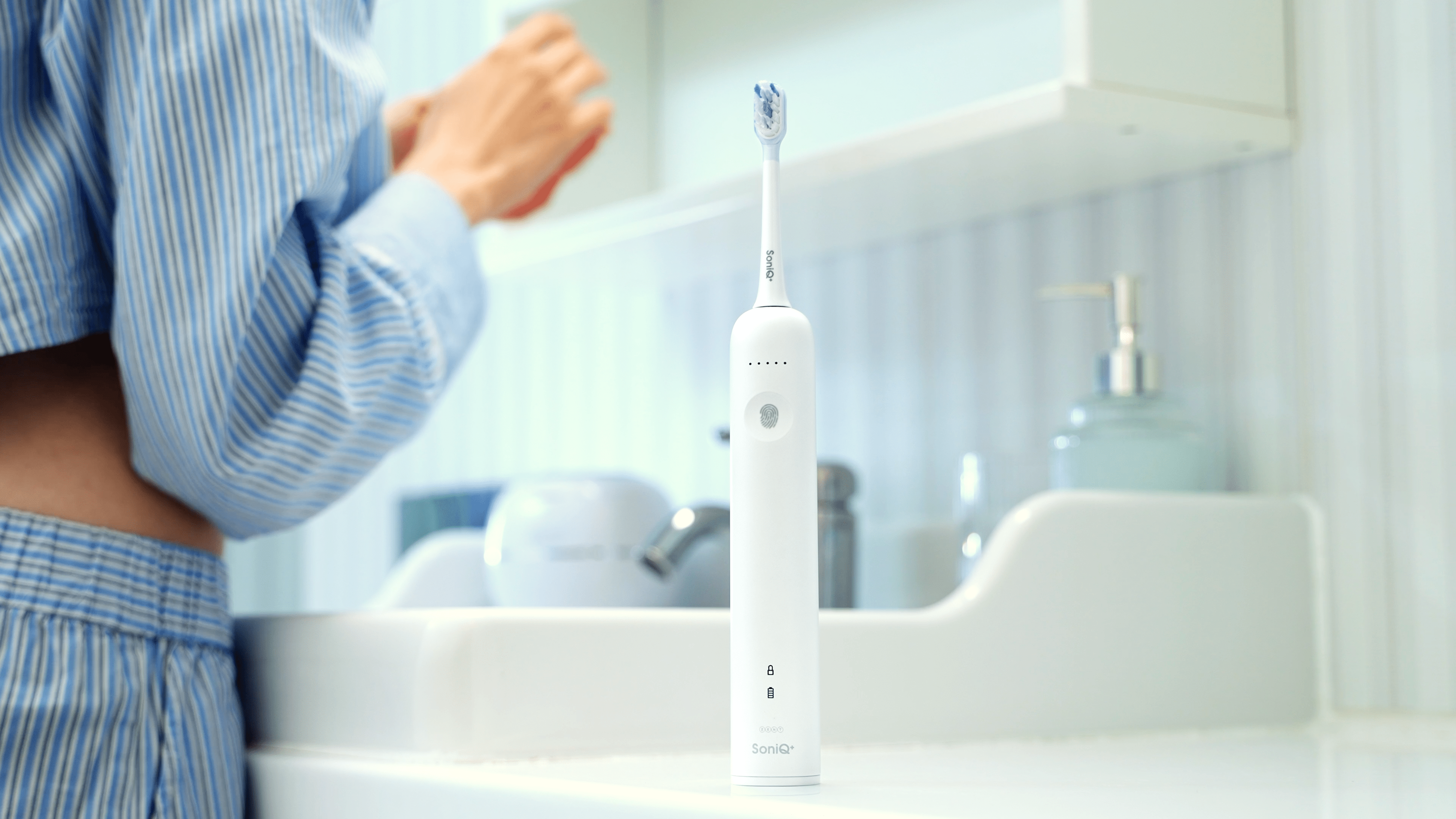 ZENT® SoniQ™ – Aktywna szczoteczka soniczna z ruchem oscylacyjnym 40° stojąca w łazience obok umywalki, w tle kobieta w piżamie